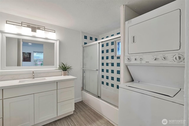 11427 Military Rd, Seattle, WA 98168 - full bathroom featuring stacked washer / dryer, vanity, combined bath / shower with glass door, a textured ceiling, and wood finished floors