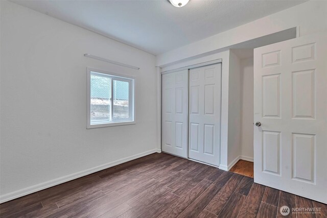 11427 Military Rd, Seattle, WA 98168 - unfurnished bedroom with dark wood-type flooring, a closet, and baseboards