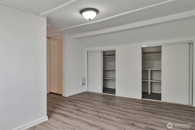 11427 Military Rd, Seattle, WA 98168 - unfurnished bedroom with baseboards, wood finished floors, and two closets