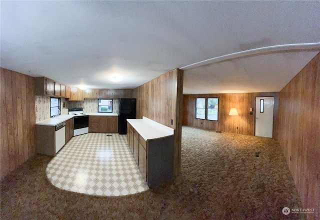 kitchen with stainless steel dishwasher, wood walls, white range oven, and light carpet