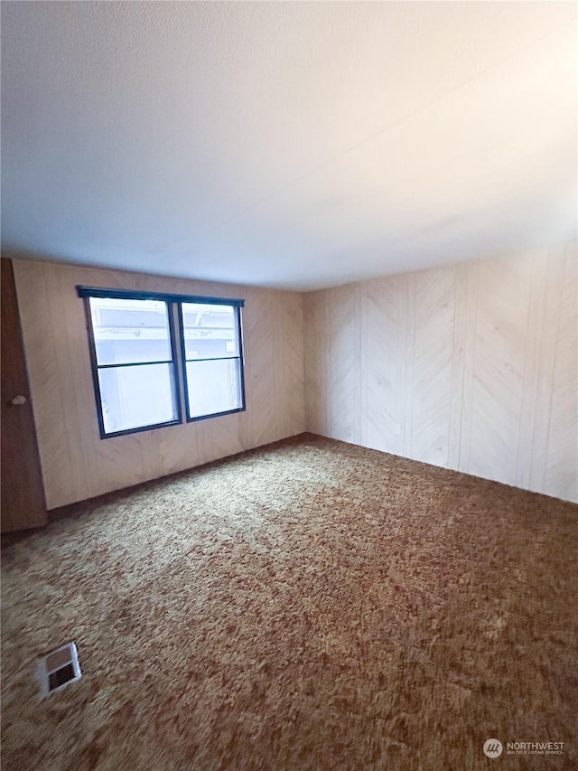 empty room featuring carpet flooring and wooden walls