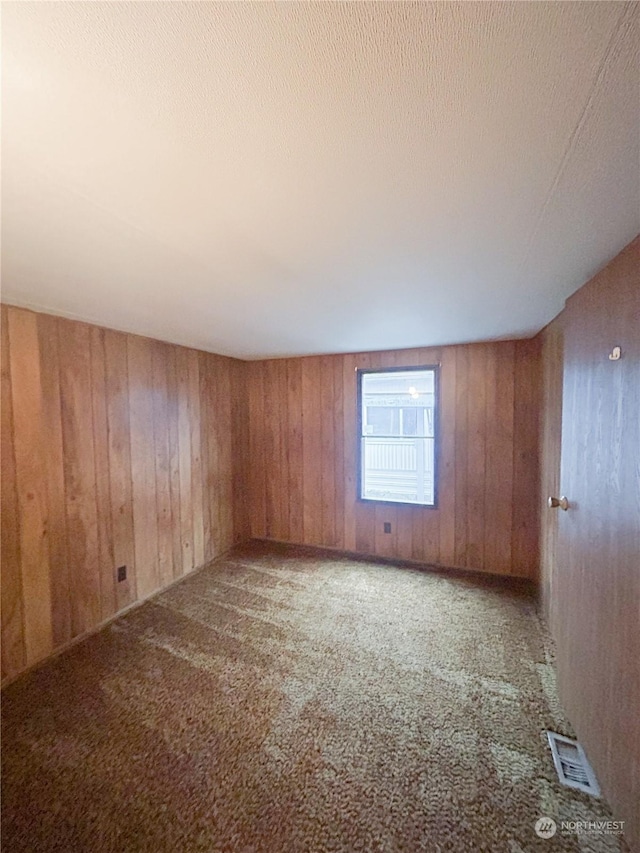 carpeted spare room with wood walls