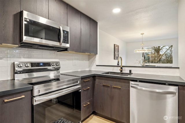 kitchen with dark brown cabinetry, sink, stainless steel appliances, and a notable chandelier