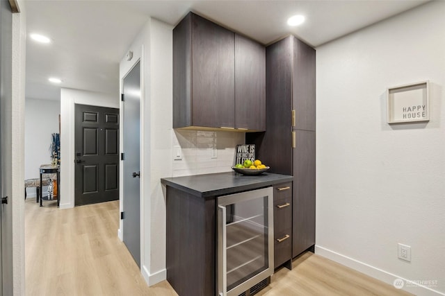 kitchen featuring tasteful backsplash, wine cooler, dark brown cabinets, and light hardwood / wood-style floors