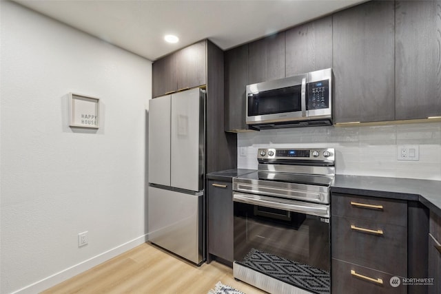 kitchen with decorative backsplash, appliances with stainless steel finishes, and light hardwood / wood-style flooring