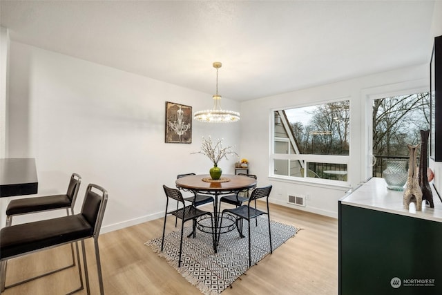 dining room with light hardwood / wood-style floors and an inviting chandelier