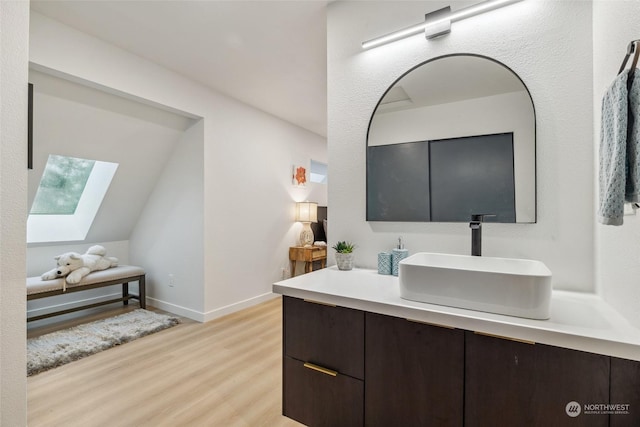 bathroom with vanity, hardwood / wood-style flooring, and lofted ceiling with skylight