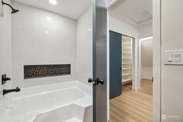 bathroom with wood-type flooring and a tub