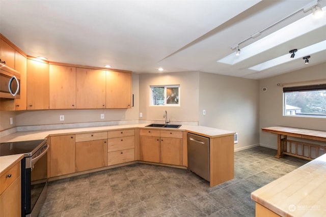 kitchen with appliances with stainless steel finishes, light countertops, a sink, and a peninsula