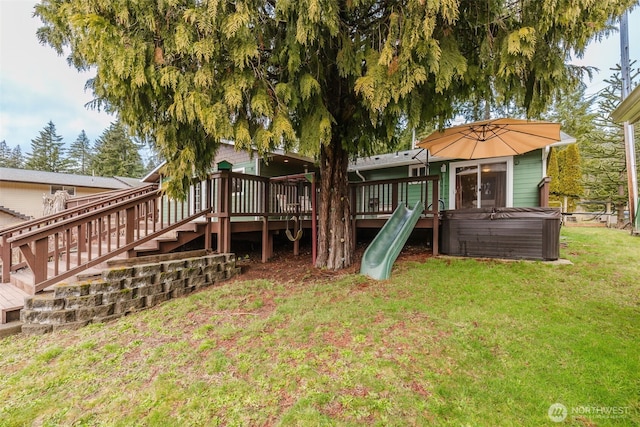 view of playground featuring a lawn, a wooden deck, and a hot tub