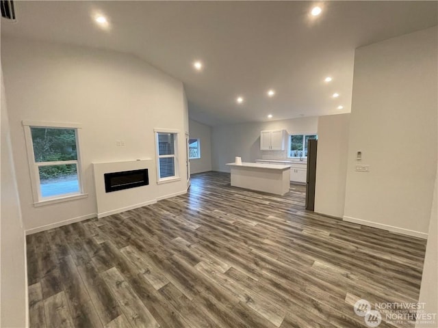 unfurnished living room with dark hardwood / wood-style flooring and vaulted ceiling