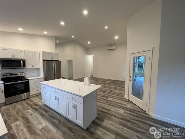 kitchen with light stone countertops, appliances with stainless steel finishes, a center island, and white cabinetry