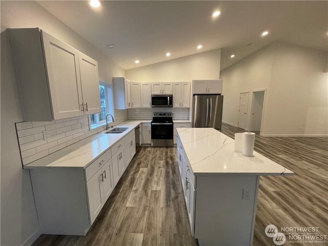 kitchen with a center island, lofted ceiling, white cabinets, sink, and stainless steel appliances