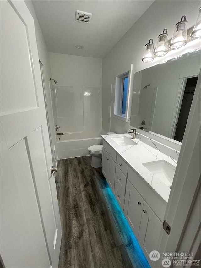 full bathroom with shower / bathing tub combination, hardwood / wood-style floors, vanity, and toilet