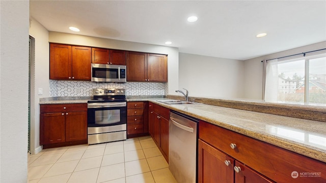 kitchen with sink, decorative backsplash, light tile patterned flooring, light stone counters, and stainless steel appliances