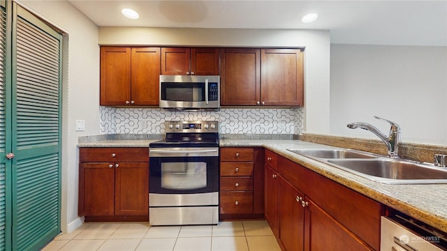 kitchen featuring backsplash, sink, light stone countertops, appliances with stainless steel finishes, and light tile patterned flooring