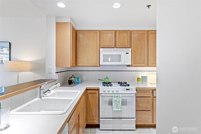 kitchen featuring tasteful backsplash, recessed lighting, light countertops, a sink, and white appliances