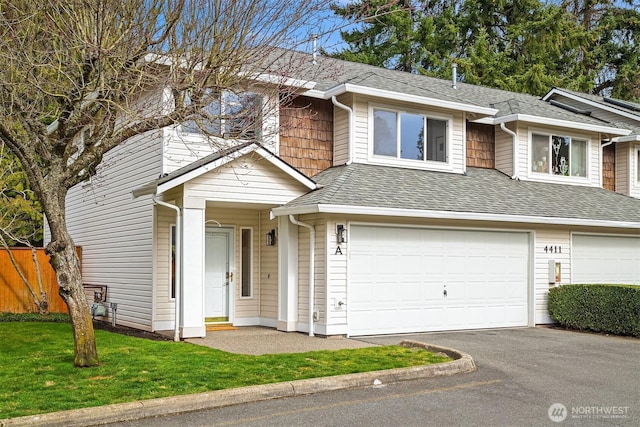 view of front of home with fence, roof with shingles, an attached garage, a front lawn, and aphalt driveway