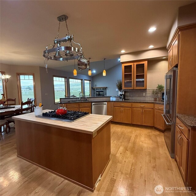 1078 Gardena Creek Rd, Touchet, WA 99360 - kitchen featuring stainless steel appliances, brown cabinetry, a sink, glass insert cabinets, and light wood-type flooring