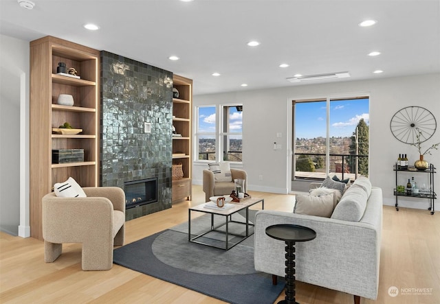 living room featuring a fireplace, built in shelves, and light hardwood / wood-style floors