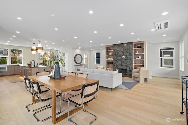 dining space with sink, a tile fireplace, and light wood-type flooring