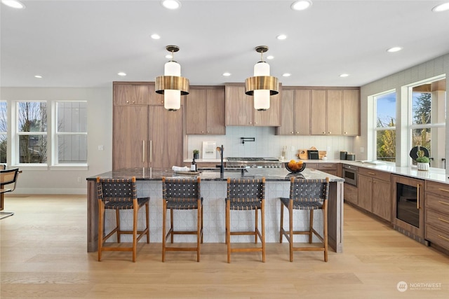 kitchen with a kitchen bar, pendant lighting, wine cooler, and an island with sink