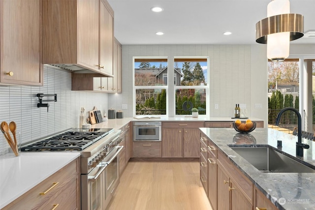 kitchen with light stone counters, appliances with stainless steel finishes, decorative backsplash, and sink