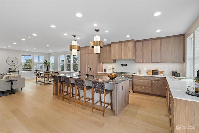 kitchen featuring a kitchen breakfast bar, light hardwood / wood-style floors, hanging light fixtures, a spacious island, and sink