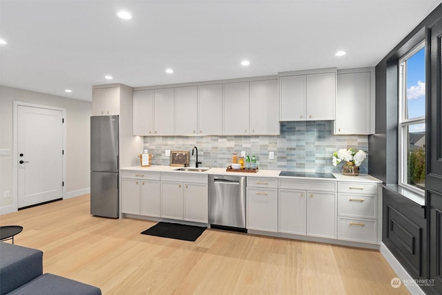 kitchen featuring sink, stainless steel appliances, light wood-type flooring, and tasteful backsplash