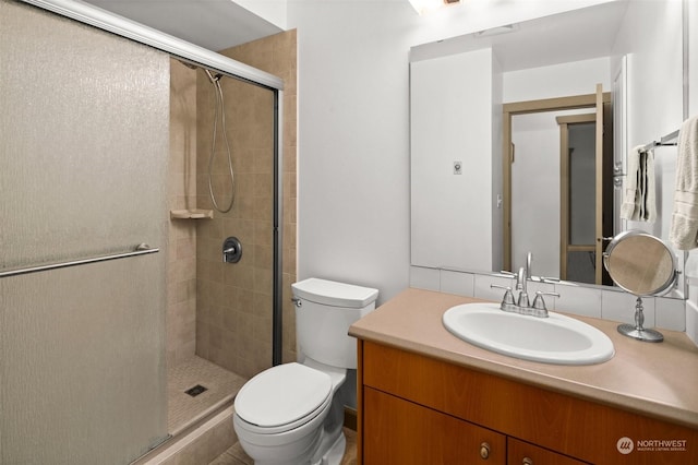 bathroom featuring a shower with door, vanity, and toilet