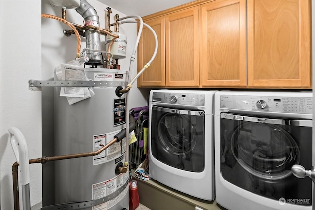 clothes washing area with cabinets, washing machine and dryer, and water heater