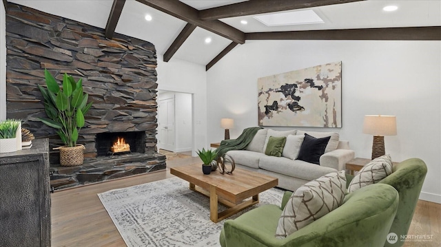 living area with a skylight, beam ceiling, a fireplace, wood finished floors, and high vaulted ceiling