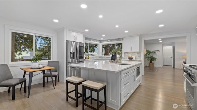 kitchen featuring stainless steel appliances, light countertops, decorative backsplash, white cabinetry, and a sink