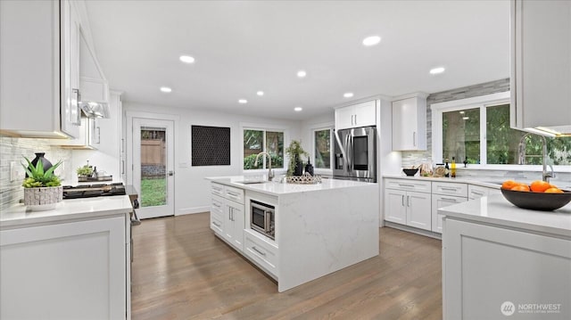 kitchen with appliances with stainless steel finishes, white cabinetry, a sink, and an island with sink