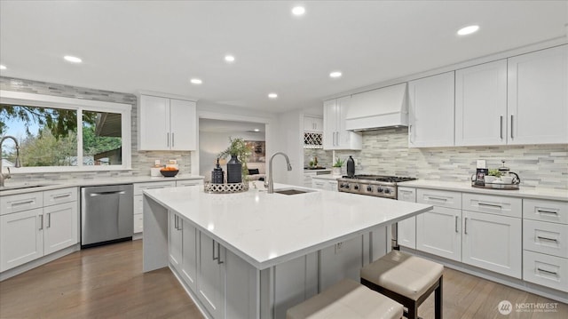 kitchen with stainless steel appliances, light countertops, custom range hood, and a sink