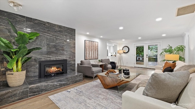 living area featuring recessed lighting, a premium fireplace, wood finished floors, visible vents, and french doors