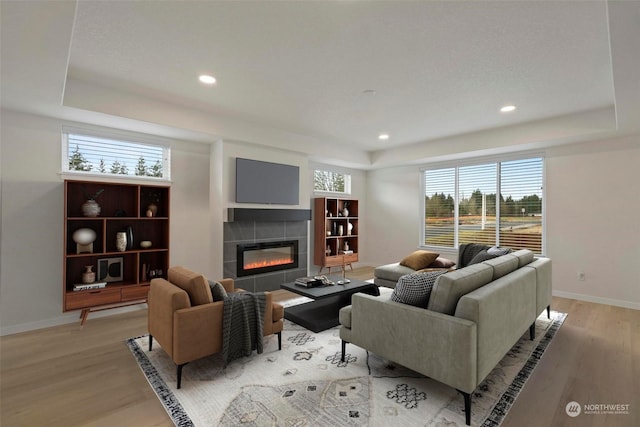 living room with a tile fireplace and light hardwood / wood-style flooring