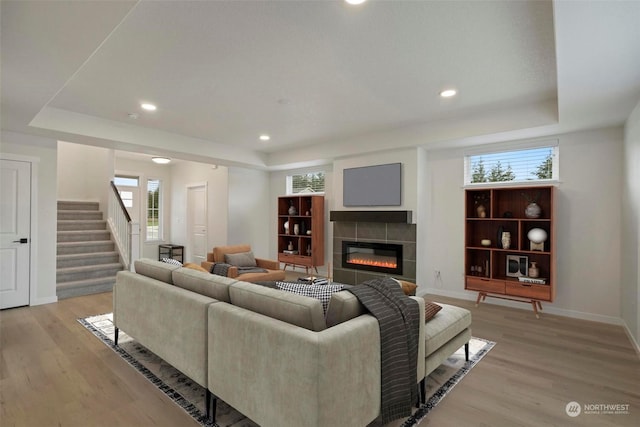 living room with a tray ceiling, a tile fireplace, and a healthy amount of sunlight