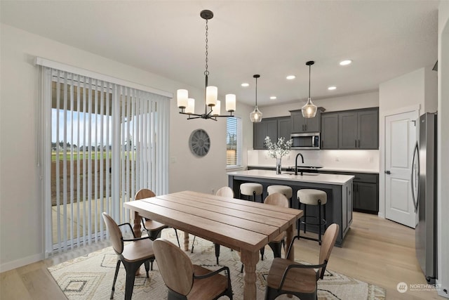 dining room featuring light hardwood / wood-style floors, plenty of natural light, a notable chandelier, and sink