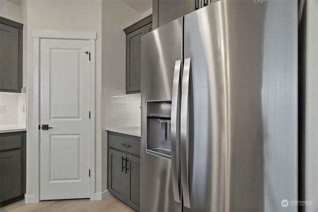 kitchen featuring gray cabinets, decorative backsplash, stainless steel fridge, and light hardwood / wood-style flooring