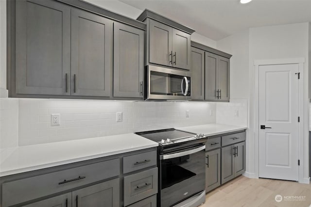 kitchen featuring gray cabinets, light hardwood / wood-style flooring, and appliances with stainless steel finishes