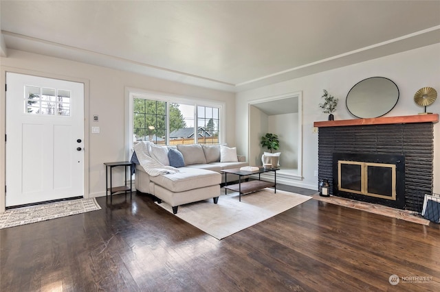 living room featuring wood-type flooring and a brick fireplace