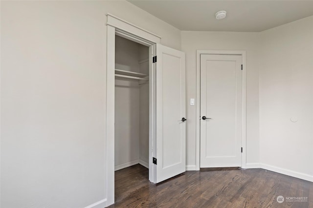 unfurnished bedroom featuring dark wood-type flooring and a closet