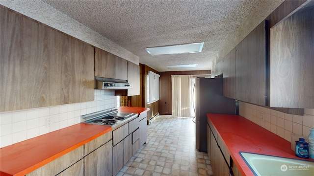 kitchen with sink, stainless steel gas cooktop, baseboard heating, ventilation hood, and fridge