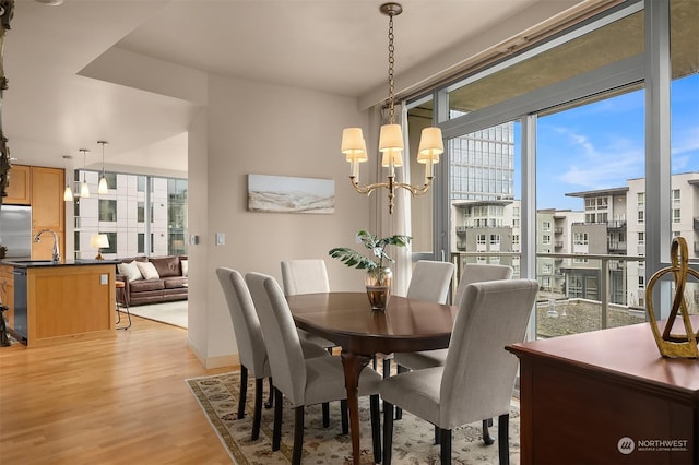 dining space featuring light wood-type flooring, a notable chandelier, and sink