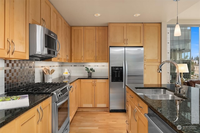 kitchen with sink, stainless steel appliances, backsplash, dark stone countertops, and decorative light fixtures