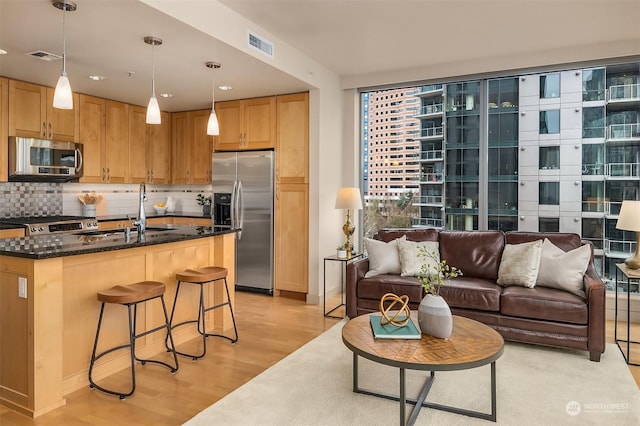 kitchen with sink, hanging light fixtures, decorative backsplash, light hardwood / wood-style floors, and stainless steel appliances