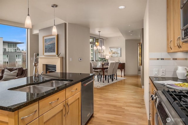 kitchen featuring dark stone counters, a kitchen island with sink, pendant lighting, and stainless steel appliances