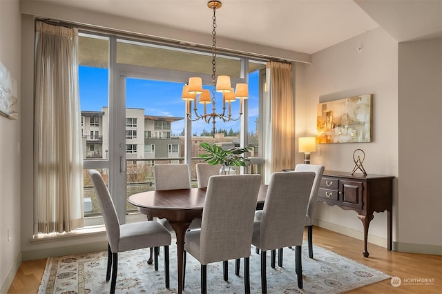 dining room with a wealth of natural light, light hardwood / wood-style flooring, and a notable chandelier