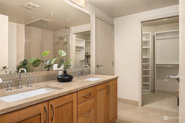 bathroom with a shower, tile patterned flooring, and vanity